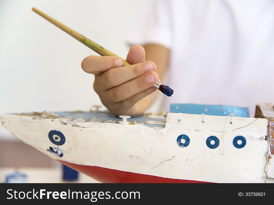Boy painting old wooden ship