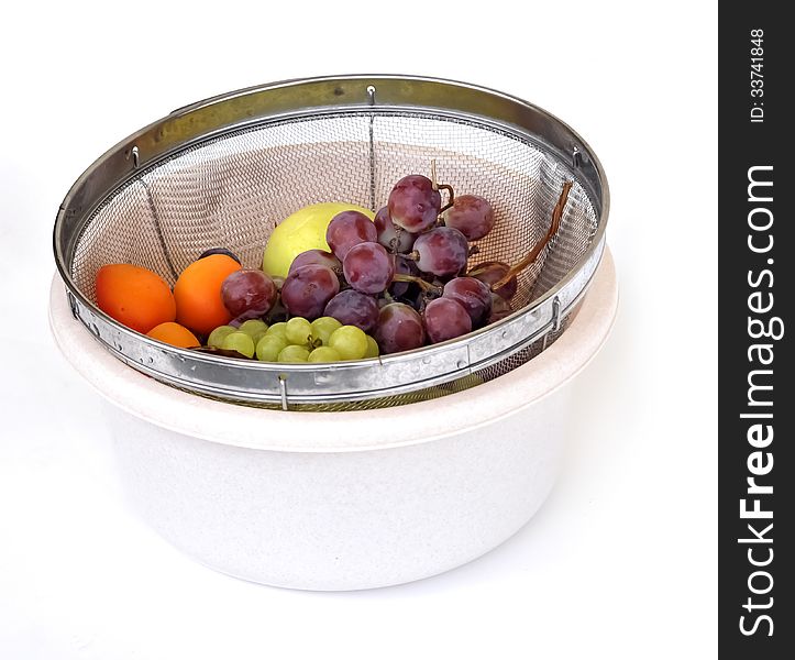 Summer fruits of grapes, apricots and apples in a strainer within a white bucket. Summer fruits of grapes, apricots and apples in a strainer within a white bucket