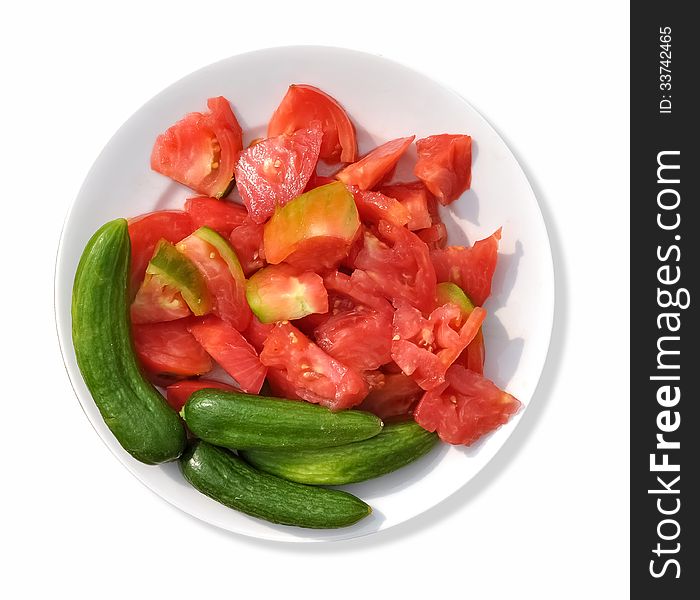 A circular white plate that contains sliced tomatoes with green cucumbers. A circular white plate that contains sliced tomatoes with green cucumbers