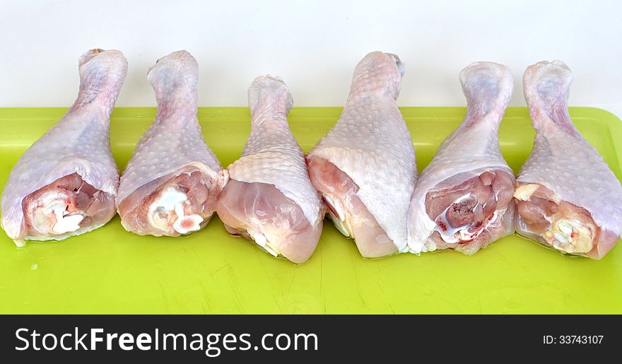 Cleaned chicken legs on a yellow plastic tray lined up horizontally. Cleaned chicken legs on a yellow plastic tray lined up horizontally