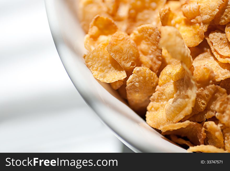 Corn flakes poured from a plate stacked on the white table closeup