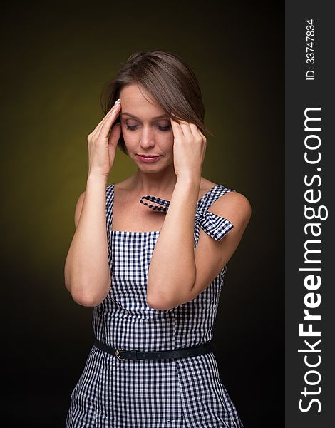 Beautiful woman with headache on golden-dark background