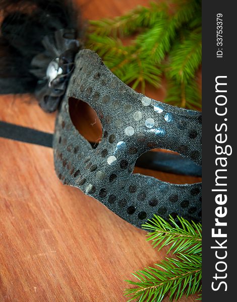 Spruce branches and carnival mask on a wooden table