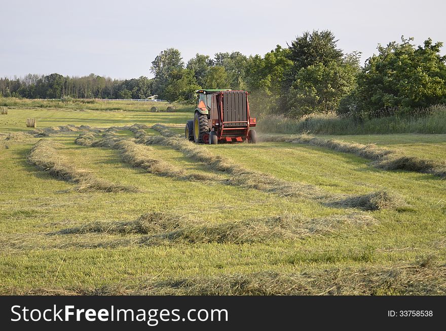 Harvesting a fresh cut field of hay in rural Michigan, USA. Harvesting a fresh cut field of hay in rural Michigan, USA