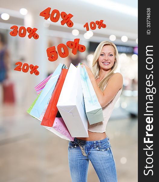 Woman with shopping bags poses at store with three-dimensional text