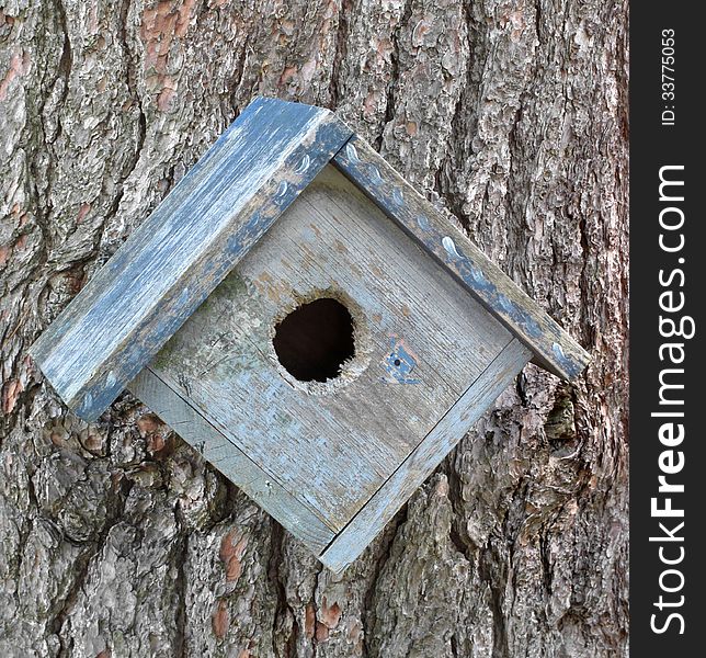 Close-up of an old and weathered wooden birdhouse on a tree. Close-up of an old and weathered wooden birdhouse on a tree.