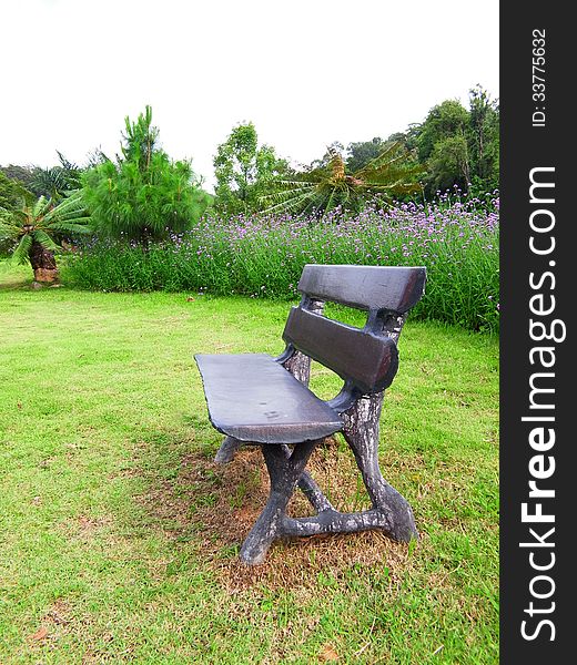 A seat made from wood is on a lawn in a botanical garden. A seat made from wood is on a lawn in a botanical garden.