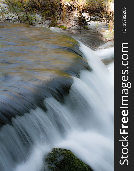 Waterfall in woods ,splashing on stone