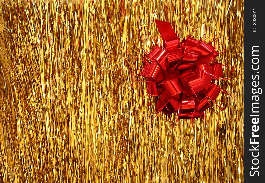 A red Christmas decoration - a ribbon shaped as a flower on golden glittering lametta strings. A red Christmas decoration - a ribbon shaped as a flower on golden glittering lametta strings.