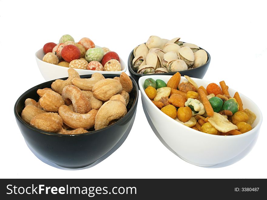 Different and tasty salted nuts in the bowls isolated on the white. Different and tasty salted nuts in the bowls isolated on the white.