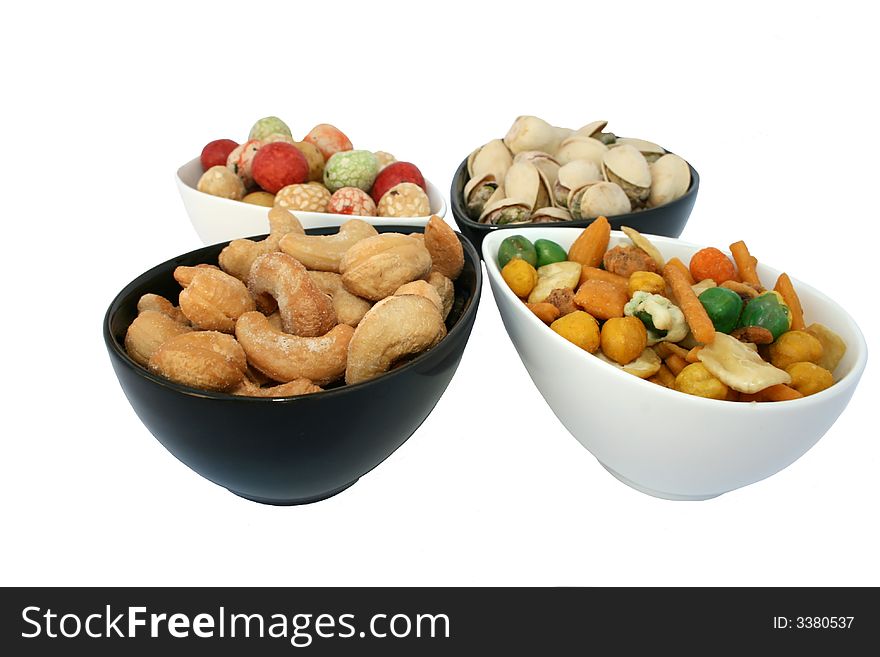 Different tasty salted nuts in the bowls isolated on the white. Different tasty salted nuts in the bowls isolated on the white.