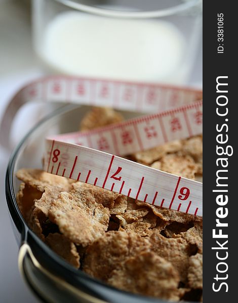 Close-up of a glass of milk, plate with cereal flakes and a measuring tape around it. Close-up of a glass of milk, plate with cereal flakes and a measuring tape around it.