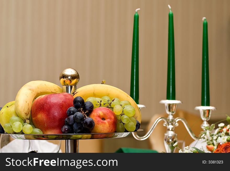 Table with fruit plate and green candles. Table with fruit plate and green candles