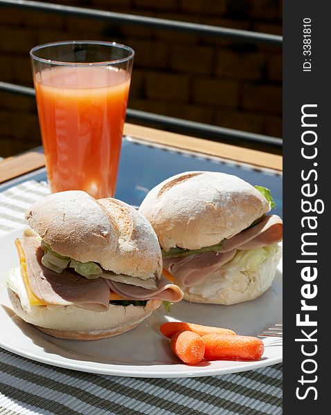 Ham and cheese sandwich on portuguese rolls served with juice