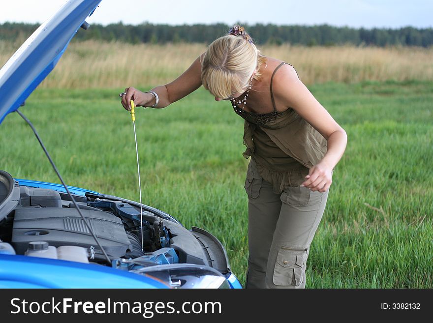 Young blond woman with her broken car. The girl is sad