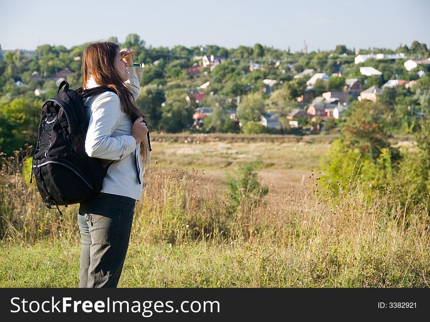 The young woman with a backpack looks afar. The young woman with a backpack looks afar