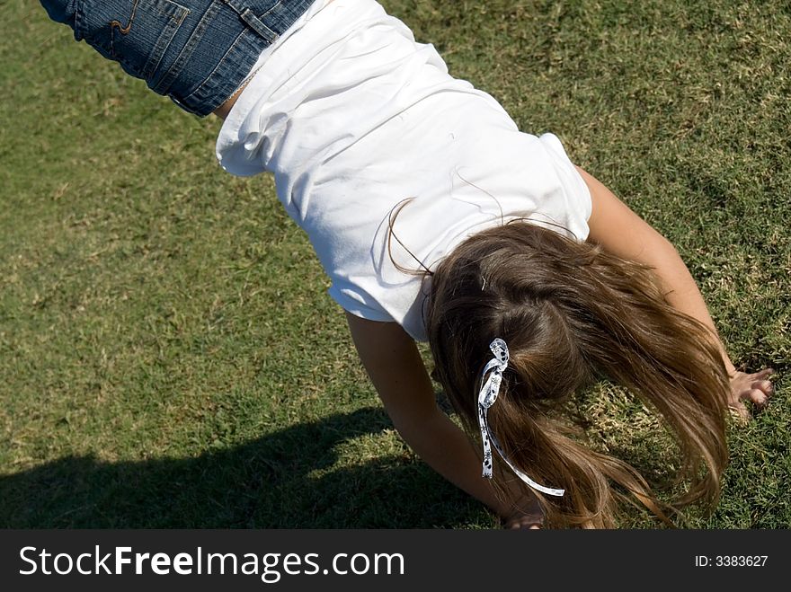 Young girl playing and doing a handstand flip. Young girl playing and doing a handstand flip.