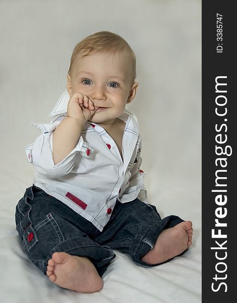 Six-month-old tot sits on shone-gray background