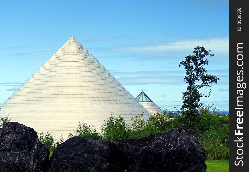 Metallic cones pointing skyward with vegetation, rocks and ocean horizon. Metallic cones pointing skyward with vegetation, rocks and ocean horizon