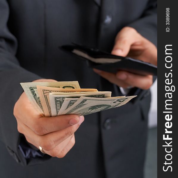 A businessman holding a wallet with dollar bills