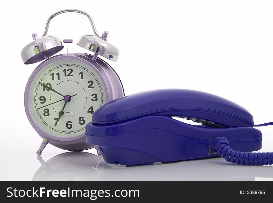 Photo of a telephone and an alarm clock over a white background. Photo of a telephone and an alarm clock over a white background