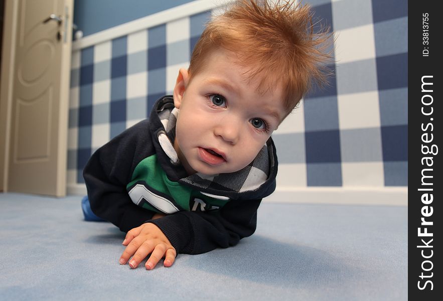 A curious baby boy lying on a floor in room at home