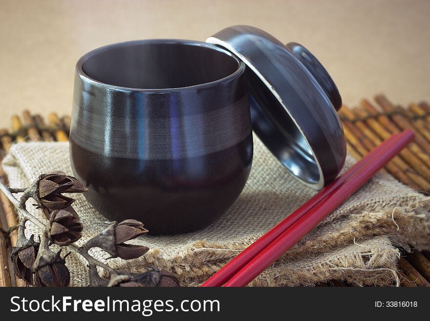 Black cup of tea with steam on brown background