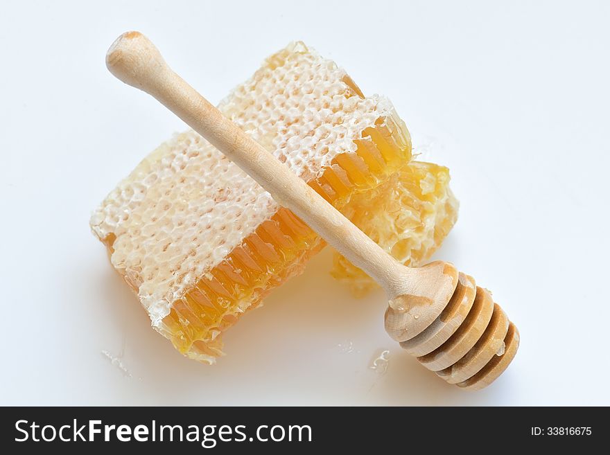 Honey in a comb and wooden spoon on white background. Honey in a comb and wooden spoon on white background