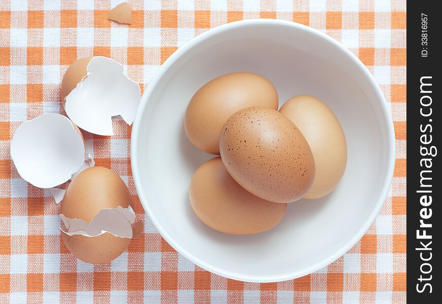 Bowl with white and yellow eggs on tablecloth background