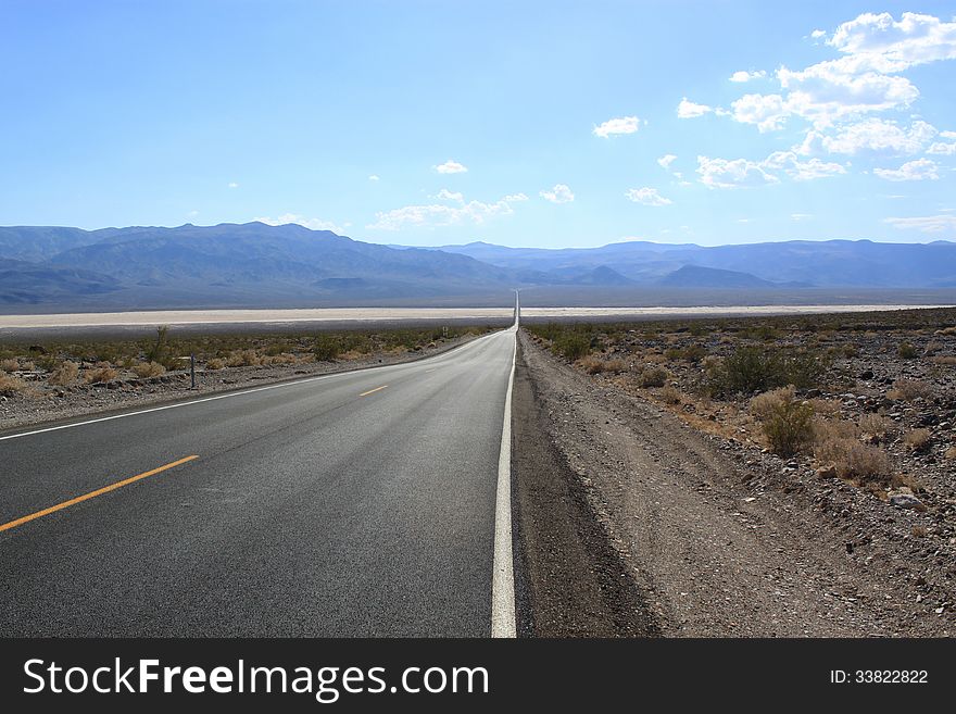 Straight asphalt road through the desert, California, USA