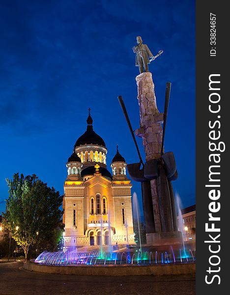 The statue of Avram Iancu surrounded by a fountain and moat, in Cluj-Napoca, Romania. Orthodox Cathedral of Cluj, Feleacu and Vadu, visible in the background. Shot at the blue hour. The statue of Avram Iancu surrounded by a fountain and moat, in Cluj-Napoca, Romania. Orthodox Cathedral of Cluj, Feleacu and Vadu, visible in the background. Shot at the blue hour.