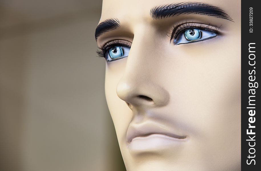 Close up of the face of a male mannequin with deep blue eyes.