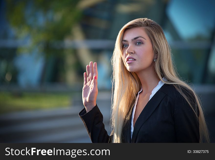 An attractive female business executive in the city with a happy look on her face and with her hand raised. An attractive female business executive in the city with a happy look on her face and with her hand raised.