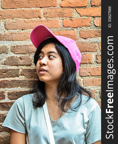 Asian girl wear hat over brick wall. Asian girl wear hat over brick wall