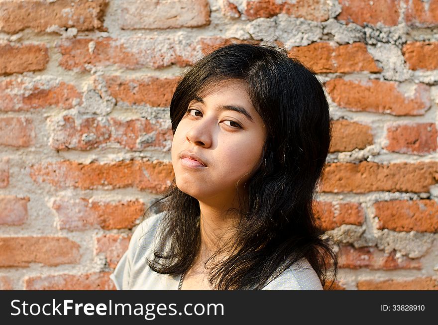 Pretentious asian girl over brick wall. Pretentious asian girl over brick wall