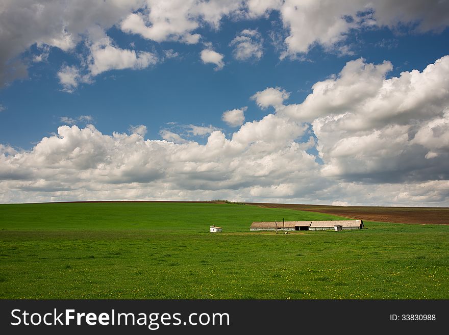 Farm in green field and blue cloudy sky. Farm in green field and blue cloudy sky