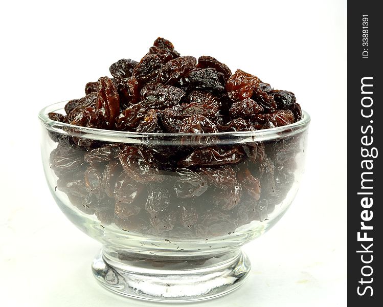 A glass bowl of raisins on a white background.