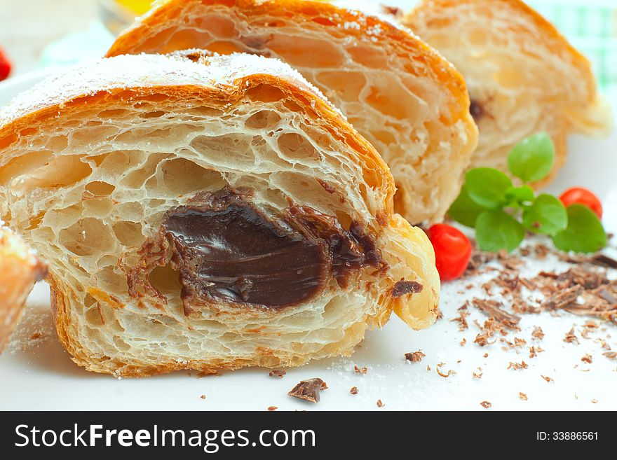 Roll with chocolate cream on a plate decorated with chocolate crumbs, herbs and berries, closeup. Roll with chocolate cream on a plate decorated with chocolate crumbs, herbs and berries, closeup