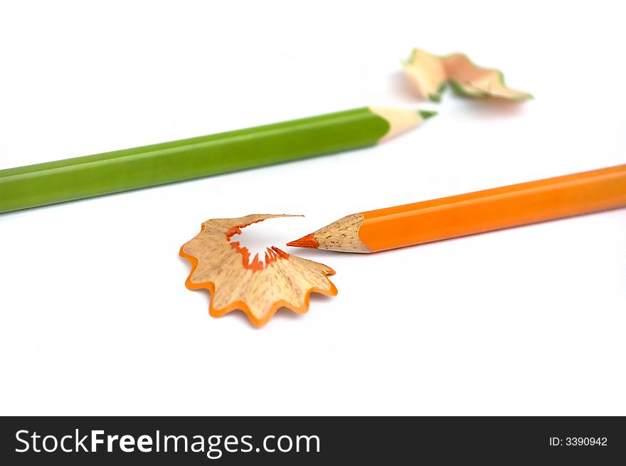 Orange and green pencils just sharpened. Opposite directions. White background. Isolated. Shallow dof. Orange and green pencils just sharpened. Opposite directions. White background. Isolated. Shallow dof.