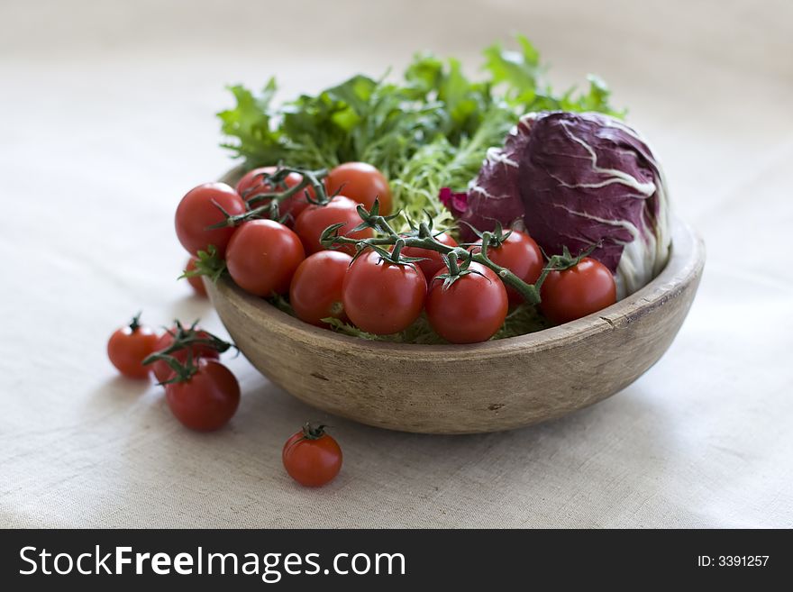 Cherry tomatoes and salad in wooden bowl