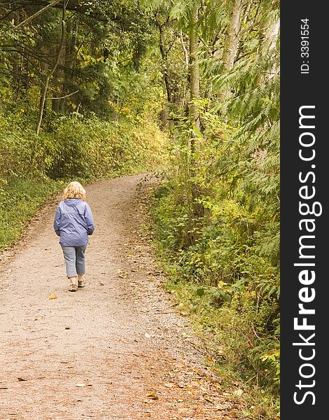 A woman walking along a woodland trail in the forest. A woman walking along a woodland trail in the forest