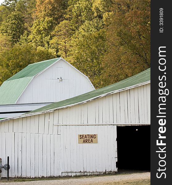 A white barn with fall trees in background. A white barn with fall trees in background