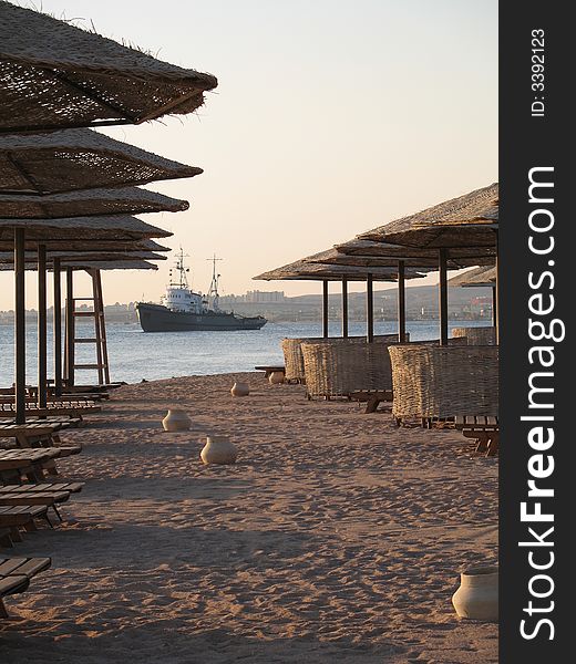 Beach, sand, umbrella, ship, sea, sun, morning, armchair, shadow, Egypt, red sea. Beach, sand, umbrella, ship, sea, sun, morning, armchair, shadow, Egypt, red sea