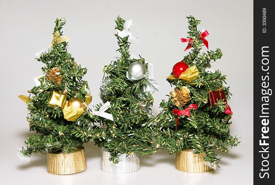 Three artificial christmas trees of green color with elegant ornaments