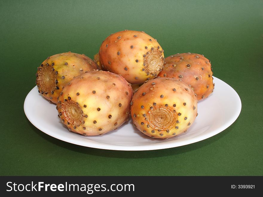 Cactus fruits on a plate on green background