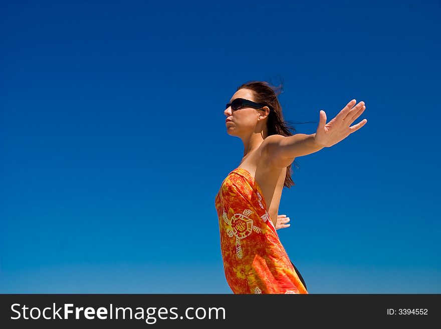 View from side of woman standing on the beach wearning orange pareo placed on the sky. View from side of woman standing on the beach wearning orange pareo placed on the sky