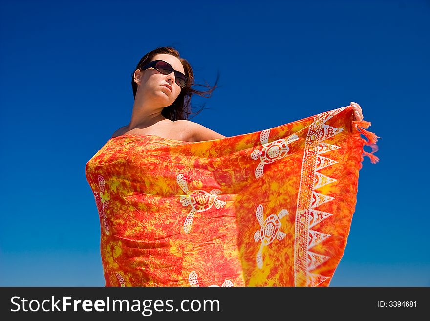 View from side of woman standing on the beach wearning orange pareo placed on the sky. View from side of woman standing on the beach wearning orange pareo placed on the sky