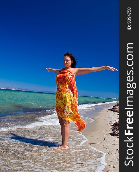 View from side of woman standing on the beach wearning orange pareo placed on the sky. View from side of woman standing on the beach wearning orange pareo placed on the sky