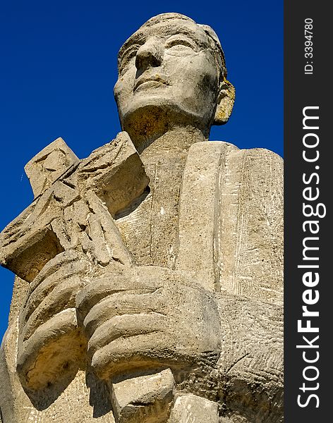 Stone statue of a priest with a cross in his hands. Stone statue of a priest with a cross in his hands