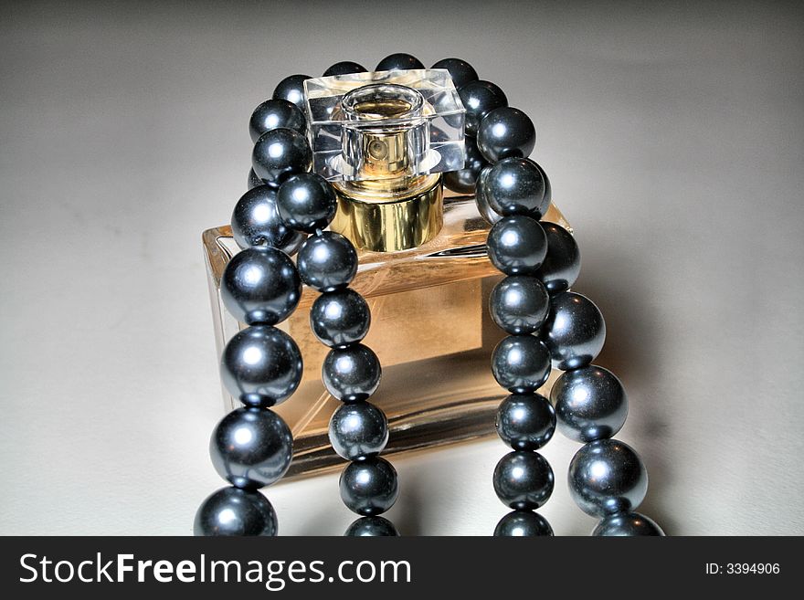 Black tahitian pearls draped over a bottle of perfume. Black tahitian pearls draped over a bottle of perfume